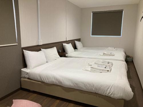 小樽RJ HOTELS OTARU的配有2张床的客房内配有白色床单和毛巾