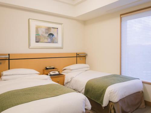 高松JR克莱门特高松酒店的带窗户的客房内的两张床