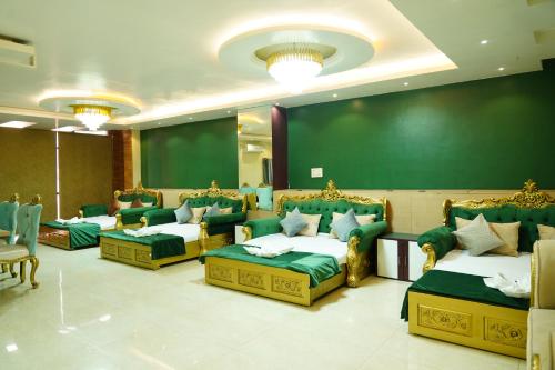 德奥加尔MAHARAJA DORMITORY的一间会议室,配有四张床和绿色的墙壁