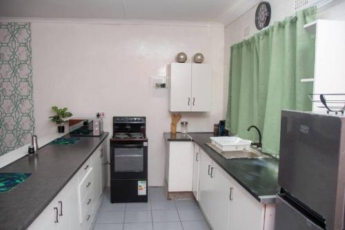 马翁Laha Apartment 3的厨房配有白色橱柜和黑色冰箱。
