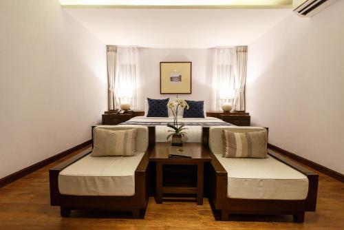 清迈清迈兰特瑞酒店的一间卧室配有一张带两把椅子和一张桌子的床。