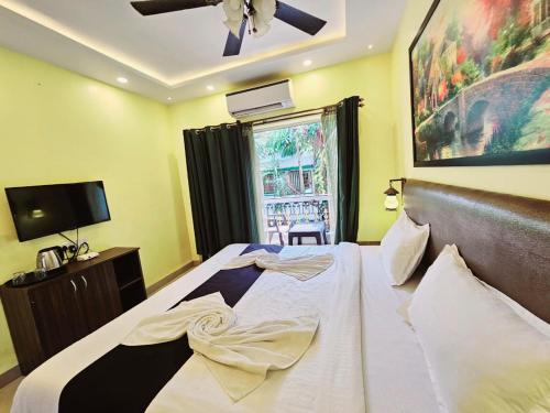 巴加Hotel Adam's Baga Beach Resort Goa - 2 minutes walk from Baga Beach的一间卧室配有一张大床和吊扇