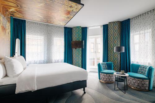 阿姆斯特丹Eden Hotel Amsterdam的一间卧室配有一张床和两张蓝色椅子
