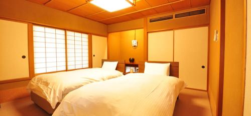 新发田市Ryokan Imai的一间卧室设有两张床和窗户。