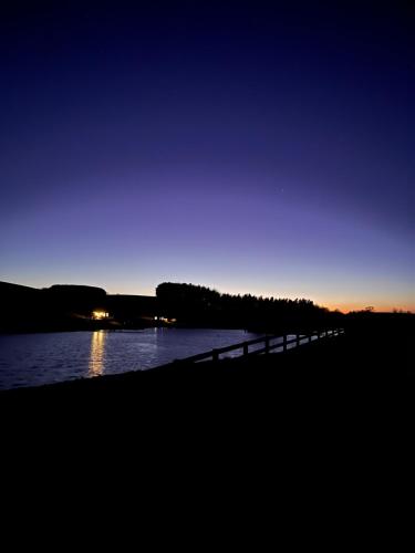 Cornhill-on-tweedEast Learmouth Lakeside Lodges的夜间在水体上方的桥梁