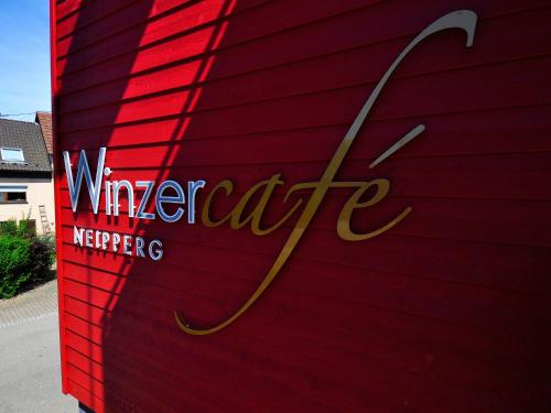 BrackenheimWinzercafe Neipperg Ferienwohnungen的红色的墙,有葡萄园的慈悲标志