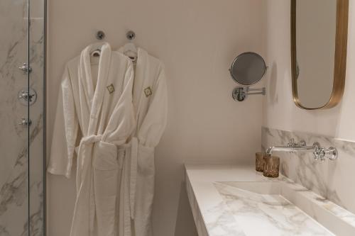 斯鲁伊斯De Lindenhoeve Boutique Hotel的浴室设有挂在水槽旁的浴袍