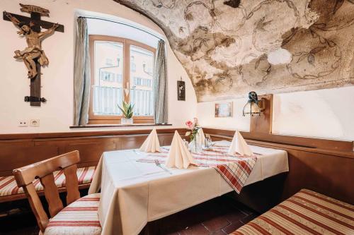 劳芬Gasthof Greimel的一间设有桌子和墙壁十字架的用餐室