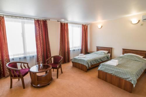 LokhvytsyaГотель Україна的酒店客房带两张床和一张桌子以及椅子。