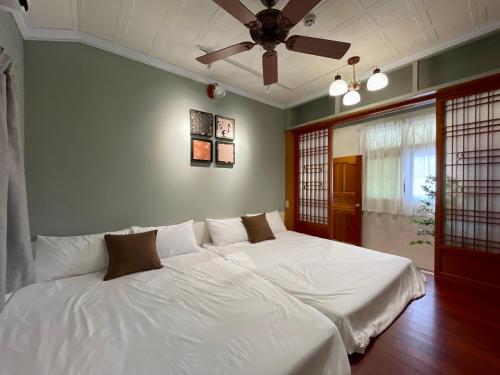 Zhuqi行滿旅宿&包棟烤肉親子寵物大庭院的一间卧室配有两张床、白色床单和吊扇