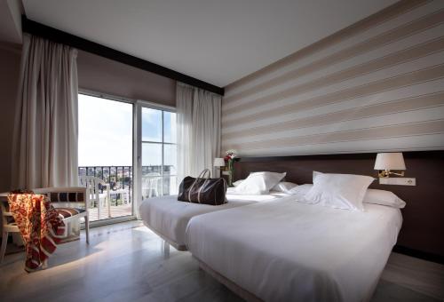 贝纳卡松Hotel Abades Benacazon的一间酒店客房,设有一张大床和一个大窗户