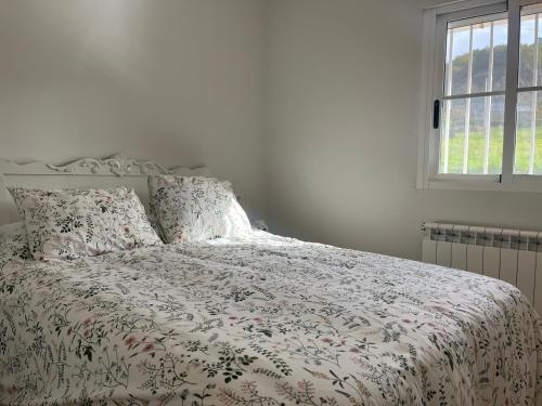 AbeledaCasa Catalina - Ribeira Sacra的一间卧室配有一张带床罩的床和窗户