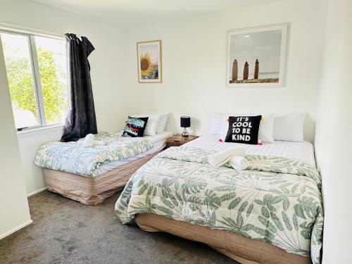 奥克兰Enjoy your stay Auckland的一间卧室设有两张床和窗户。