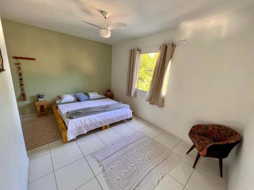 塞拉Kitnet na Vila de Manguinhos的一间卧室设有一张床、一个窗口和一把椅子