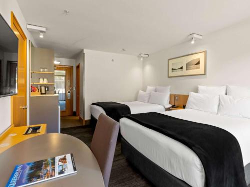 皇后镇皇后镇湖畔诺富特酒店的酒店客房设有两张床和一张桌子。