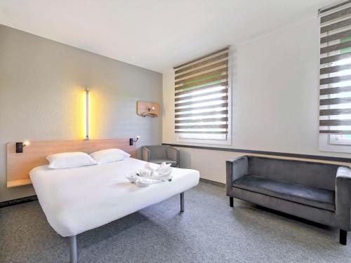 卡托维兹ibis budget Katowice Centrum的卧室配有一张白色的大床和一张沙发。