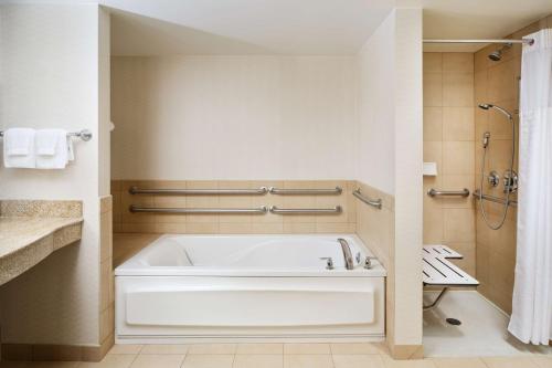 绍姆堡绍姆堡希尔顿花园旅馆的浴室配有白色浴缸和淋浴。
