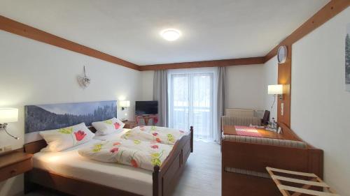 鲁波尔丁Hotel Garni Haus Alpine - Chiemgau Karte inkl的一间卧室配有一张床、一张桌子和一张四柱床。