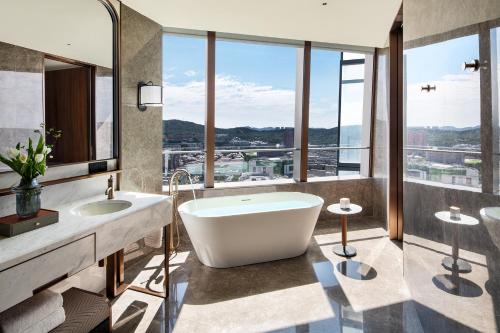 大连大连四季酒店的带浴缸和两个盥洗盆的浴室以及窗户。