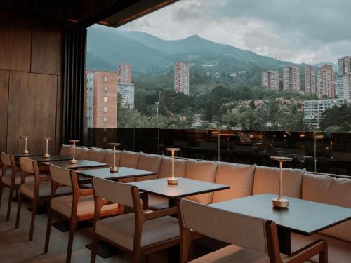 麦德林宾恩酒店的一间设有桌椅的餐厅,享有城市美景