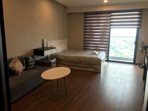 海阳Apec Mandala hotel & suites Hải Dương的一间卧室配有一张床、一张桌子和一张沙发