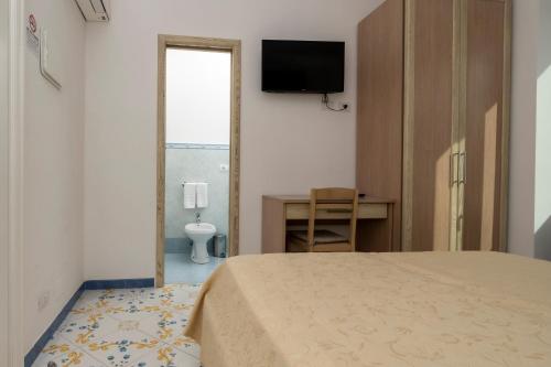 卡普里拉皮亚泽塔旅馆的一间卧室配有一张床、一张书桌和一台电视