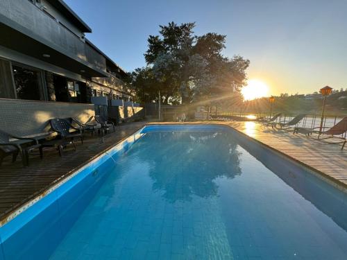 维拉卡洛斯帕兹Nuevo Hotel Ciervo de Oro- By HVH的一座建筑物后面的游泳池,阳光照耀着