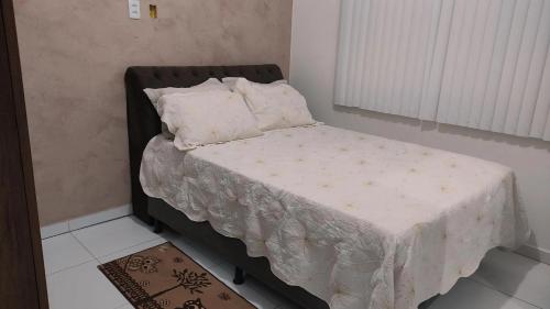 盖比姆Casa p/ temporada, praia guaibim的一张小床,位于一间白色毯子的房间
