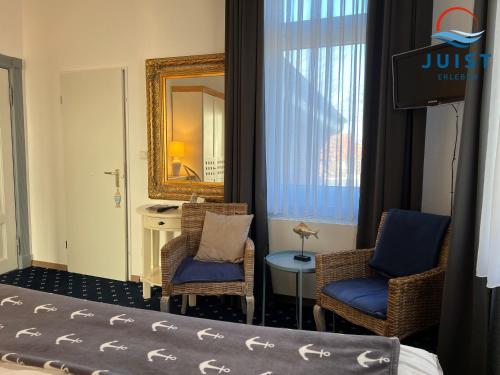 于斯德Pension Marie Luise 253 - Zimmer Meerschnecke的酒店客房带两把椅子和镜子
