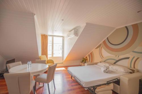 里斯本阿露比雅格兰德盘沙住宅酒店的客房设有一张床、一张桌子和一张桌子以及椅子。