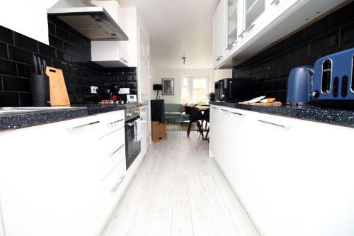 布里斯托4 BR with FREE on street parking的厨房设有黑色墙壁和白色橱柜,铺有白色地板。