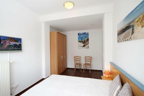 奥斯赛拜-屈隆斯博恩Strandschloesschen-Haus-I-WE-7-9866的一间卧室配有一张床和两把椅子