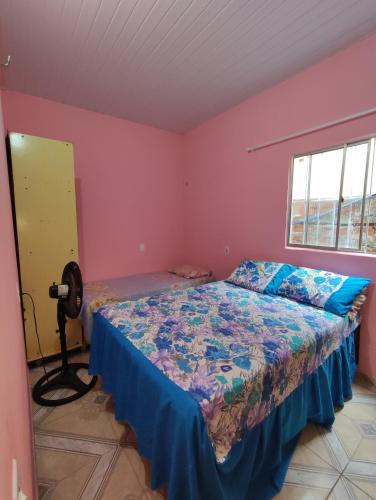 图托亚Recanto dunas的卧室配有一张床铺,位于一间粉红色墙壁的房间