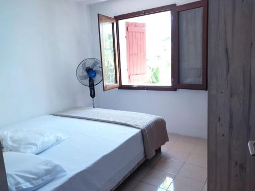 蓝海湾Oasis Appartement的一间卧室设有一张床、一个窗口和风扇