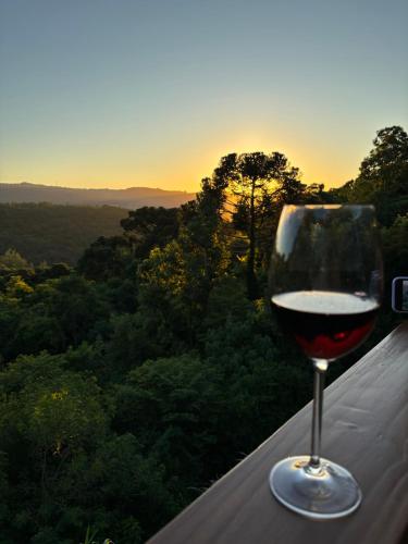 格拉玛多Reserva Linha Bonita的坐在一个享有日落美景的山 ⁇ 上喝一杯葡萄酒