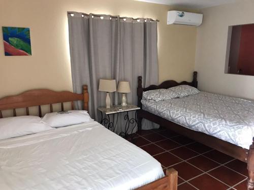 伯利兹城Bamboleo Inn的一间卧室设有两张床和窗户。