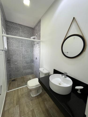 尚格里拉Casa com Piscina em Xangri-Lá RS的一间带水槽、卫生间和镜子的浴室