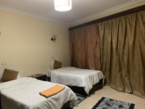 开罗Sheraton apart-hotel的客房设有两张床和一个带窗帘的窗户。