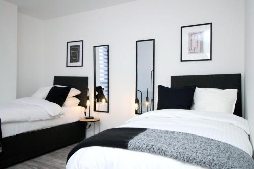 史云顿Kingsbridge Point 4 2 BR with Free Parking的卧室内的两张床,配有白色的墙壁和镜子