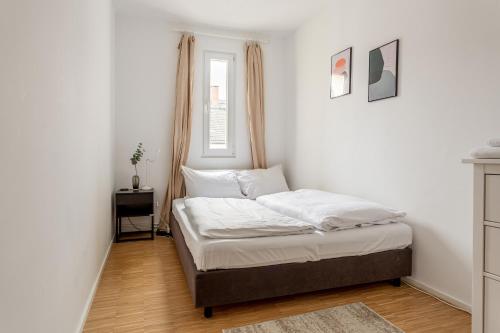 柏林Global Living - Design Apartment I Central I Smart-TV I Kitchen I Berlin的一间卧室配有一张带白色床单的床和一扇窗户。