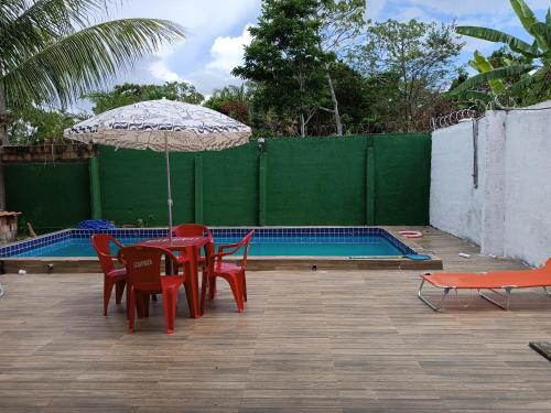 伊塔帕里卡Casa na ilha de Itaparica的游泳池旁配有遮阳伞的桌椅