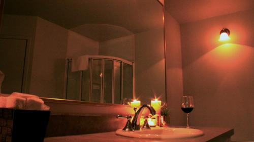AsbestosHôtel Val-des-Sources的浴室设有蜡烛水槽和一杯葡萄酒