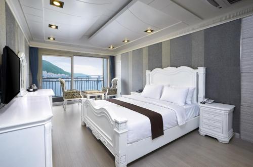 釜山Busan Beach Hotel Busan Songdo的一间带白色床的卧室和一个阳台