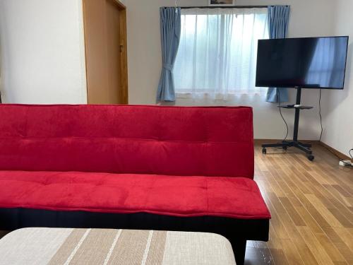 德之岛Yoka House - Vacation STAY 46247v的客厅设有一张红色沙发,配有平面电视。