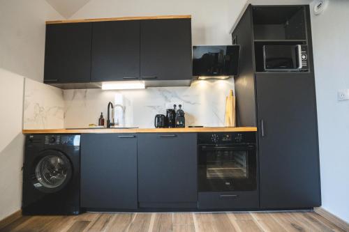 拉瓦勒LE FACTORY aux pieds de la gare SNCF Laval的厨房配有黑色橱柜、洗衣机和烘干机