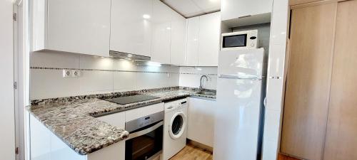 萨洛Apartamento Lauren Salou的厨房配有白色橱柜和白色冰箱。