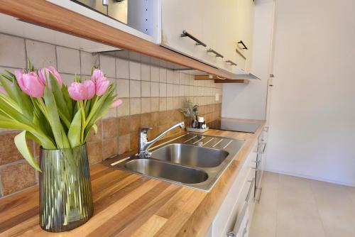 图尔库Cozy 93m² Townhouse with Large Terrace & Sauna的厨房配有水槽和花瓶中的粉红色花卉