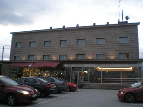 圣西普安－德比尼亚斯圣西伯来酒店的停车场内有车辆的建筑物