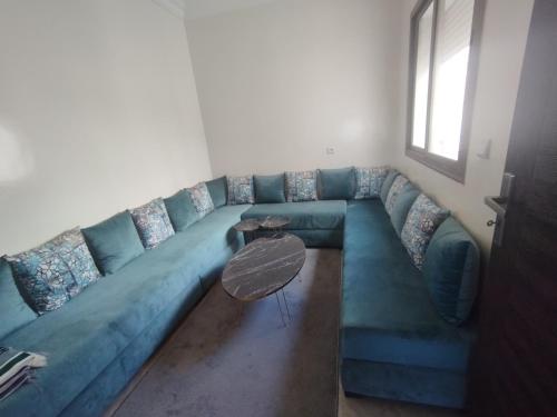 Ben YakhlefAppartement Cozy Louizia的客厅配有一张蓝色的沙发,配有一张桌子