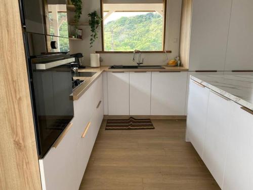 拉特里尼泰Villa Cannelle -charmante et tout confort的厨房配有白色橱柜和窗户。